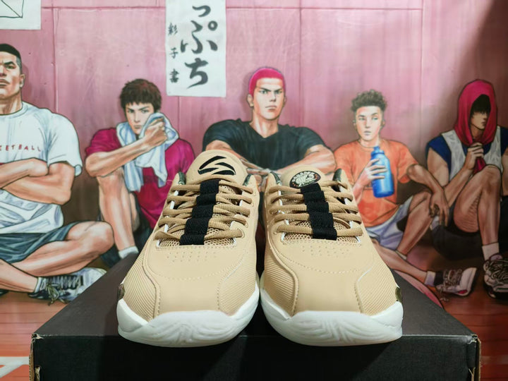 Front view of beige Jordan basketball sneakers with black laces and white textured outsoles on a black box.