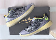 Pair of black and gray sneakers arranged diagonally over a black presentation box.