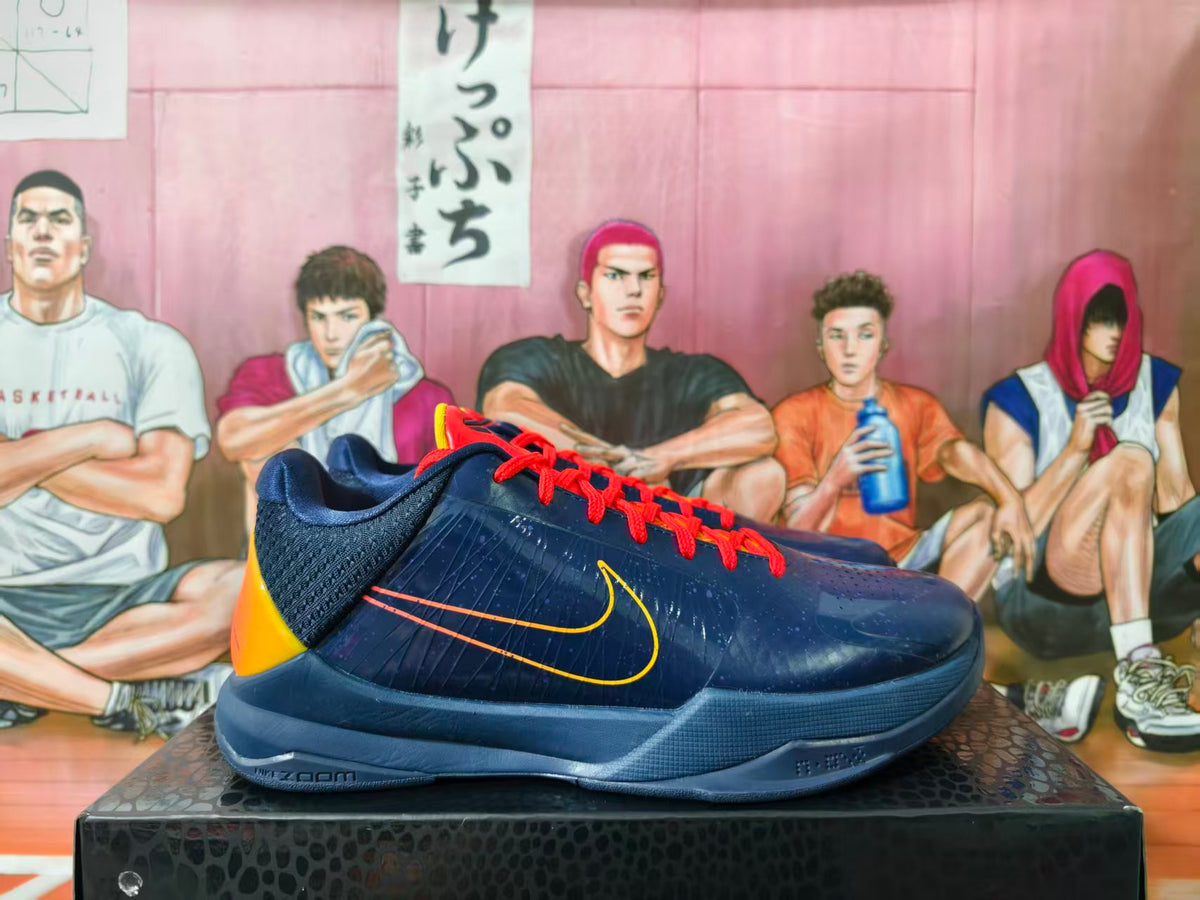 Side view of navy Nike Kobe basketball shoes with orange-red laces and yellow-orange accents
