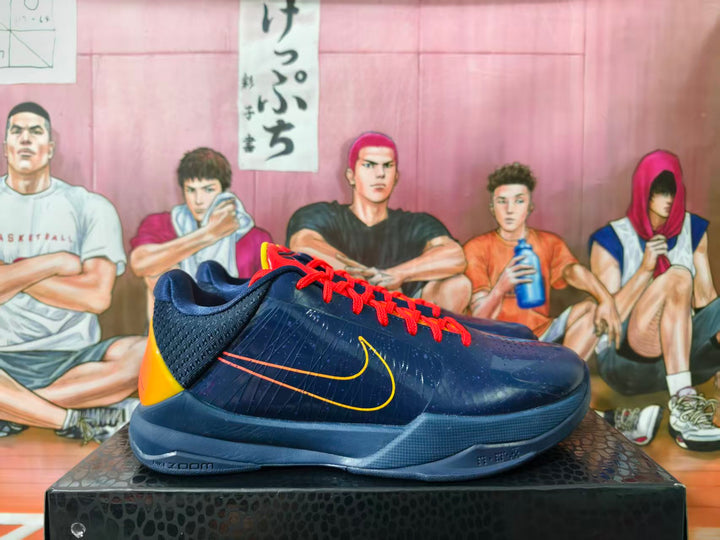 Side view of navy Nike Kobe basketball shoes with orange-red laces and yellow-orange accents