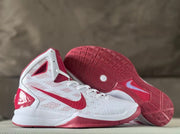 White and red basketball shoes shown with one outsole facing up.