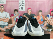 Pair of white, black, and blue Adidas basketball shoes shown from the front.