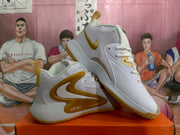 Angled side view showing the white Nike basketball sneakers, yellow-gold Swoosh accents, lace-up design, and padded collars.