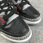 Close-up of the black textured toe area, black laces, red eyelets, and grey elephant-print mudguard.