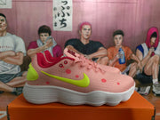 Side profile of a pink Nike sneaker with red dot accents, a lime-green swoosh, and a white ribbed outsole.