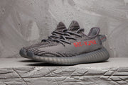 Side view of a dark grey patterned sneaker with grey laces, red side lettering and a translucent ribbed outsole.