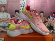 Angled view of the pink Nike sneaker pair showing the lime-green swooshes, red dot accents, and white outsoles.