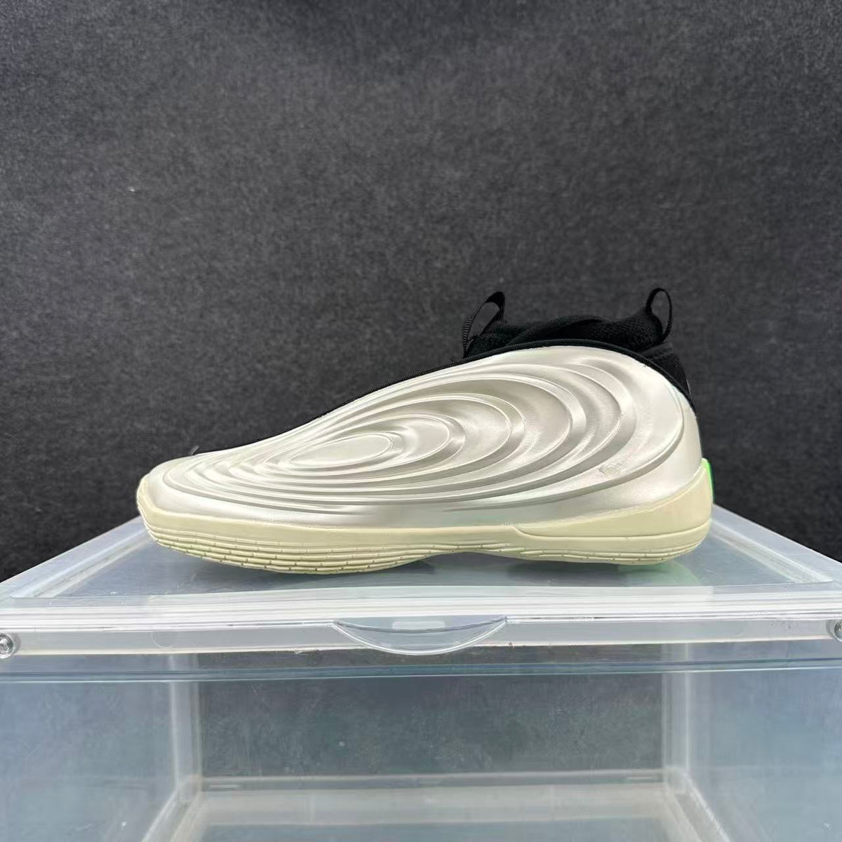 Side view of a silver and black sneaker showing its layered sculpted sidewall and cream-toned sole.