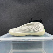 Side view of a silver and black sneaker showing its layered sculpted sidewall and cream-toned sole.