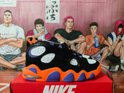 Side view of black Nike basketball-style sneakers with white panels, orange and purple sole accents, and visible heel cushioning.