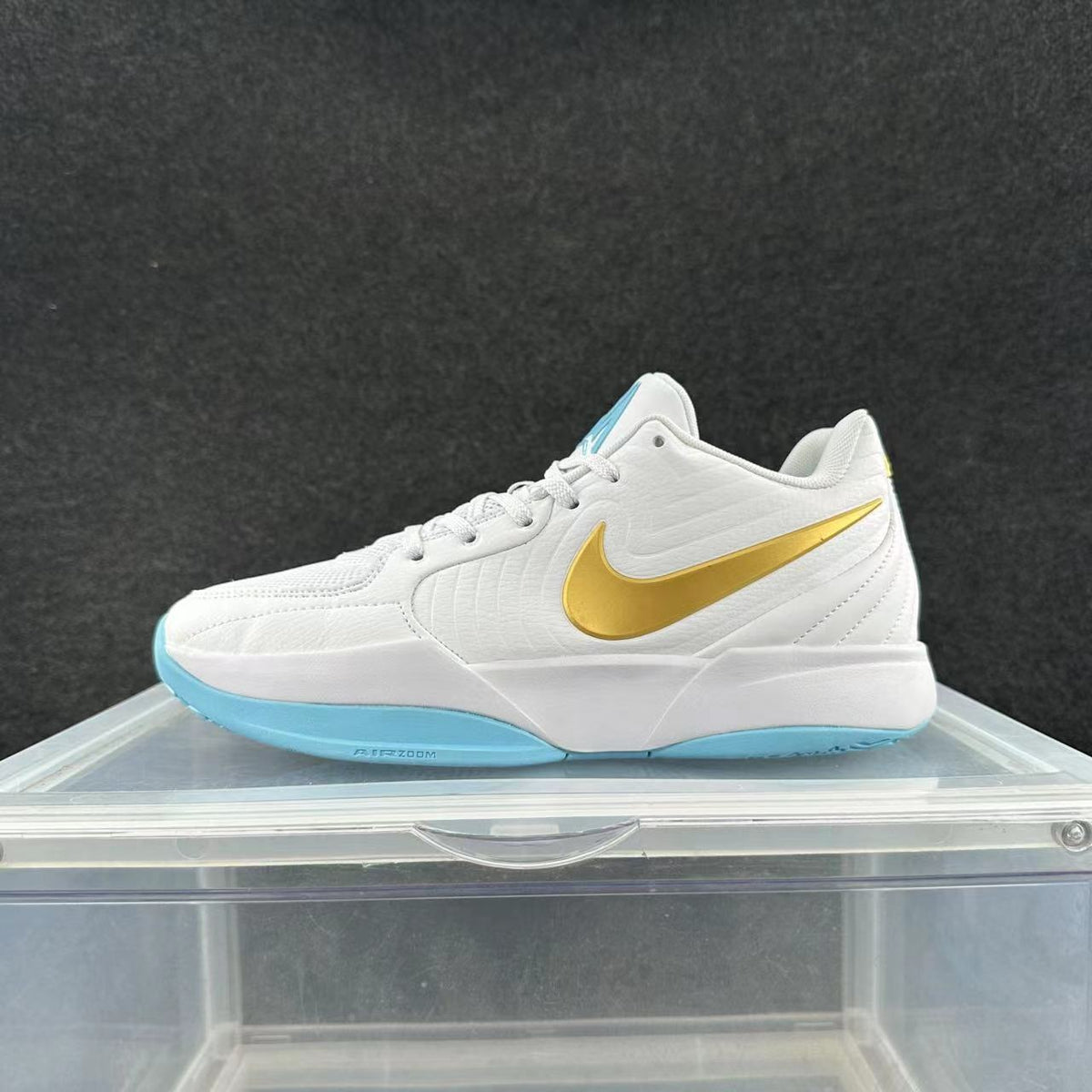 Side view of a white Nike basketball sneaker with a gold Swoosh and light-blue outsole accents.