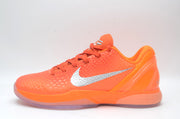Side view of a bright orange Nike basketball sneaker showing the textured upper, silver Swoosh, orange laces, and translucent outsole.