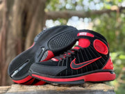 Pair of black and red high-top sneakers with one shoe tilted to show the patterned outsole.