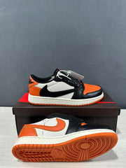 Two black, orange and white low-top sneakers shown from the side and outsole, highlighting the orange traction pattern.