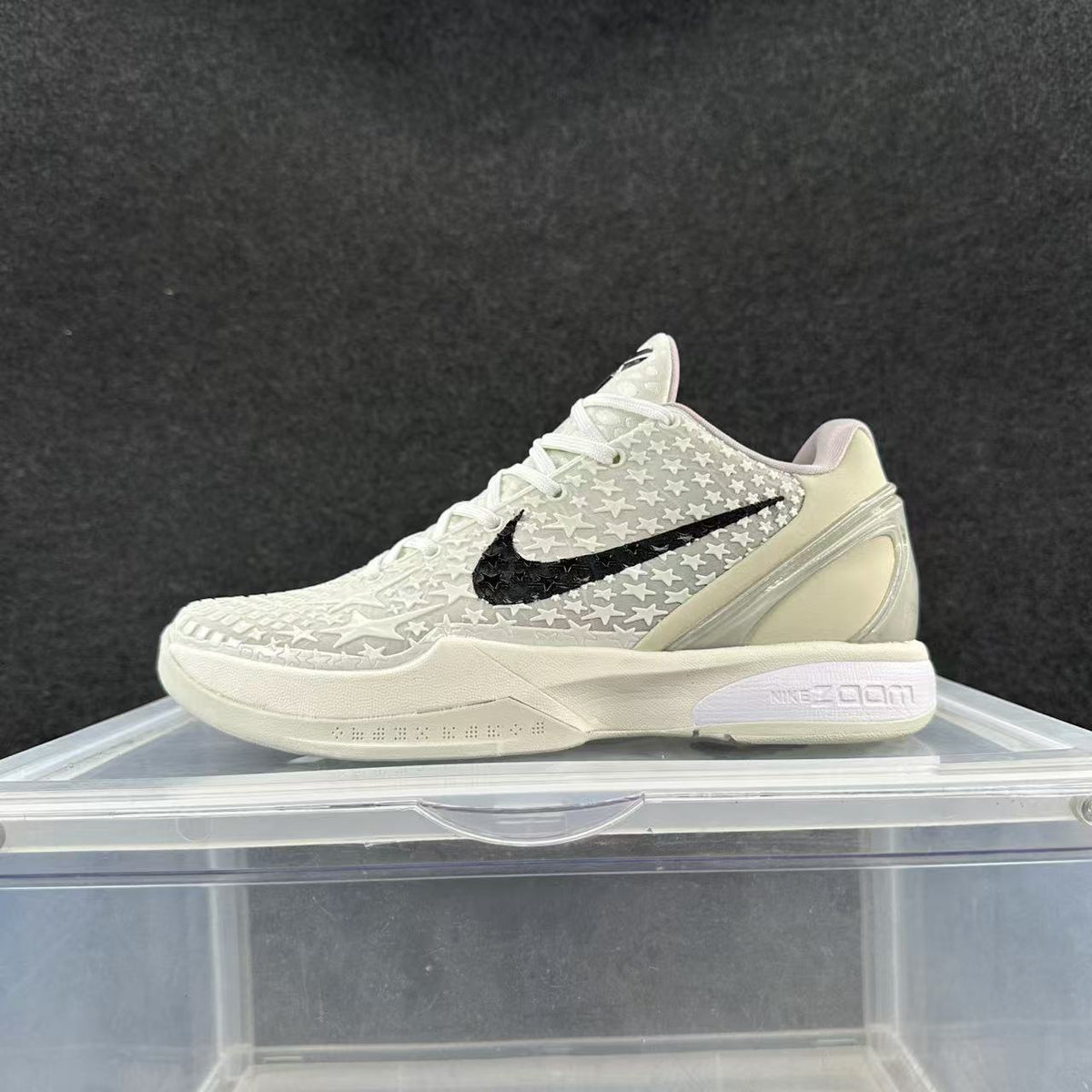 Side view of an ivory-toned Nike basketball sneaker with raised star details, a black Swoosh, and a pale Zoom-branded midsole.