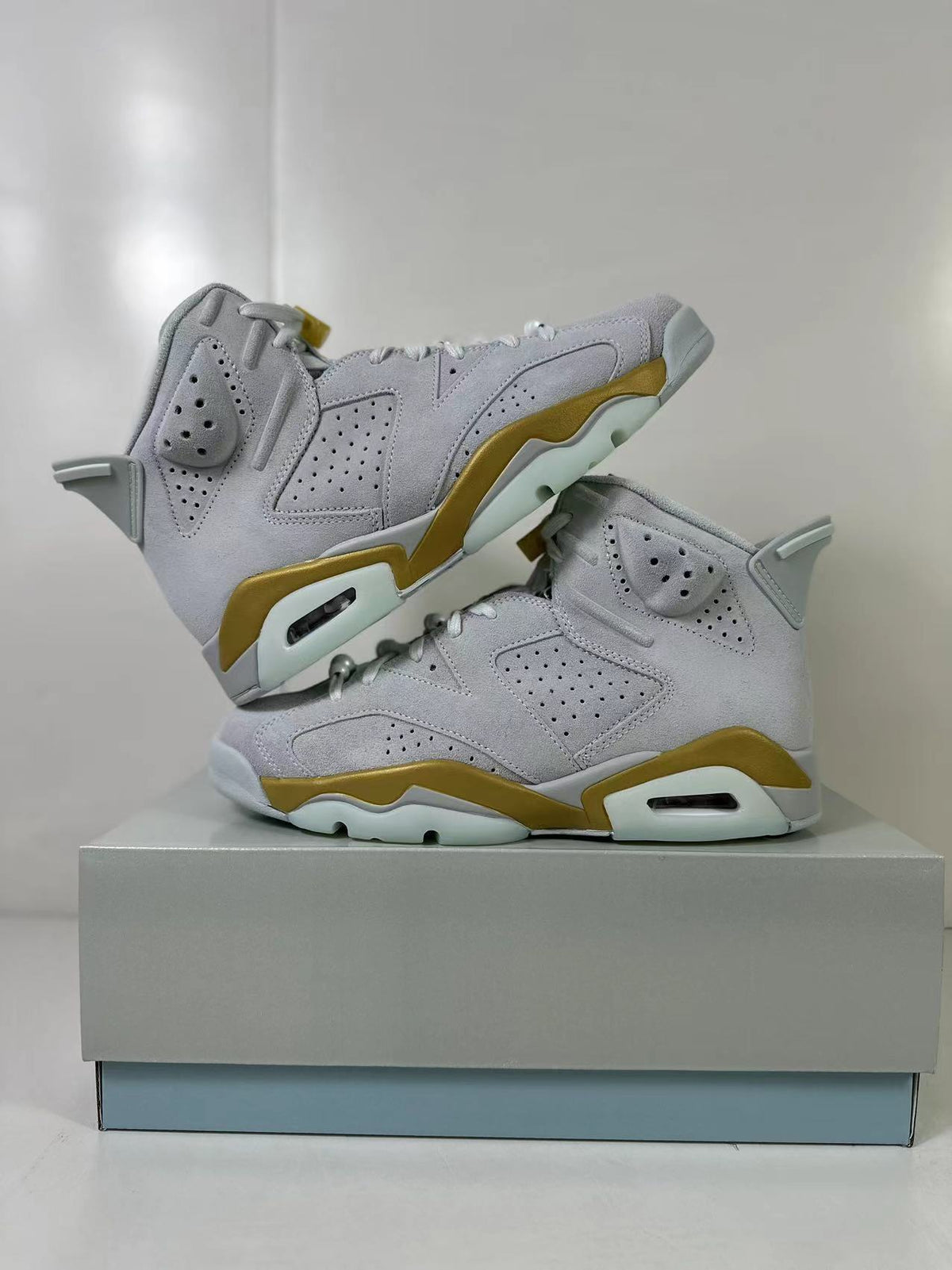 Pair of white and gold Jordan Air Jordan 6 high-top sneakers displayed on a box.