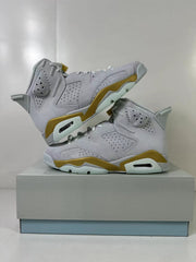Pair of white and gold Jordan Air Jordan 6 high-top sneakers displayed on a box.