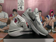 Angled view of white and black Nike GT Cut shoes showing the striped upper and sculpted soles.