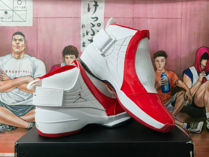 White and red Jordan high-top sneakers displayed on a black shoebox, showing the ankle strap, side branding, and contrasting outsole.