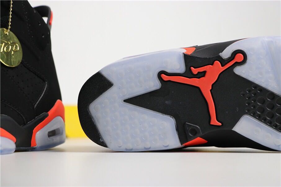Close-up of the black sneaker outsole with translucent sections and a bright infrared Jordan emblem.