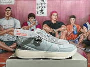 Side view of a white and grey Nike low-top sneaker with lace-up closure and basketball-themed side emblem.