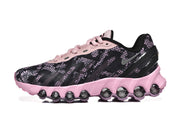 Side view of a black patterned Nike Air Max DN8 sneaker with a pink sole and rounded cushioning elements.