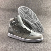 Pair of grey, silver and white high-top Jordan sneakers shown from the front, with one outsole facing upward.