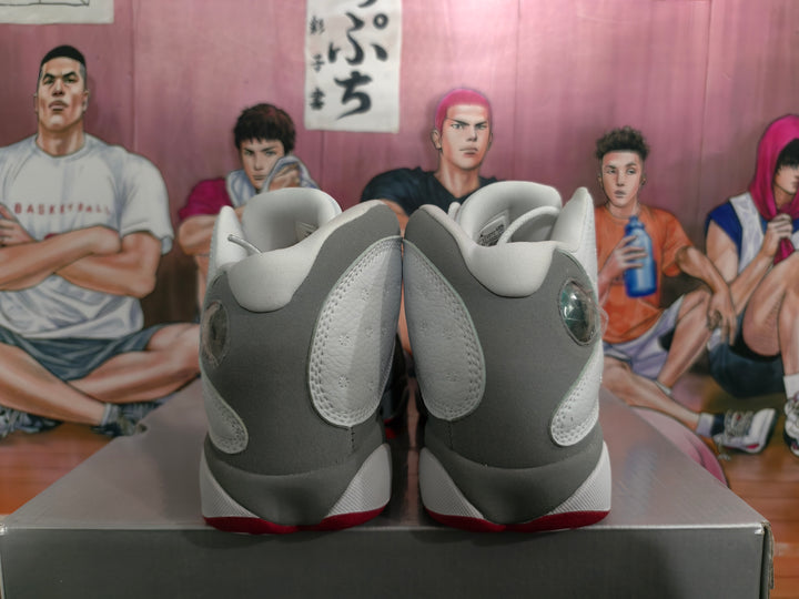 Rear view of white and gray high-top Jordan sneakers showing padded collars, layered heel panels, and red outsole accents.