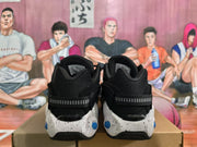 Rear view of black Nike-style sneakers with textured collars, heel straps, and white speckled midsoles with blue accents.