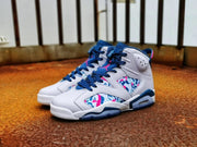 Pair of multicolor Air Jordan 6 sneakers shown from a front three-quarter angle on a floor.