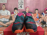 Front view of Nike high-top basketball sneakers with pink tongue flaps, dark teal and red camouflage-style panels, black toe overlays, and orange outsole sections.