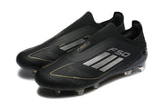 Pair of black adidas F50 laceless soccer cleats with silver side stripes and gold detailing.