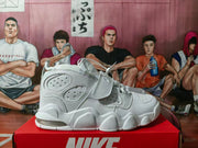 Side view of a white Nike high-top sneaker showing layered perforated panels, a fastening strap, and a visible heel air unit.