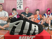 Side view of a black and white Nike sneaker showing contrasting panels, cutout details, and a chunky outsole.