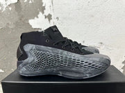 Side view of a black Adidas high-top basketball shoe with a textured grey side panel and marbled outsole.