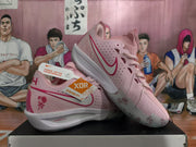 Side view of pink Nike basketball sneakers with perforated panels, red Swoosh detailing, floral heel graphics, and ZoomX branding.