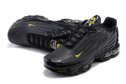 Angled view of black Nike Air Max Plus III sneakers with gold details.