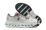 Side view of a white and mauve On Cloudmonster 3 shoe with its patterned outsole visible behind it.
