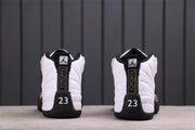 Rear view of a pair of white and black Air Jordan 12 sneakers with gold detailing