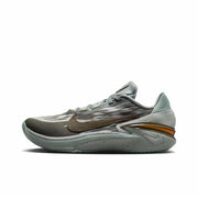 Gray Nike GT Cut 2 sneaker with a darker Swoosh, speckled gray sole, and orange heel accent.
