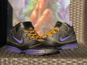 Front three-quarter view of the high-top sneakers with black uppers, yellow laces, and purple midsoles.