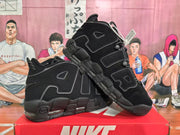 Angled view of the black Nike sneaker pair highlighting the AIR side lettering, textured panels, and chunky sole.