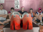 Rear view of the white and bright orange basketball shoes with contrasting heel details.