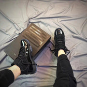 Black sneakers worn with a matching presentation box visible beside them.