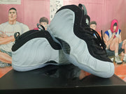 Angled view of the white and black high-top sneakers displaying the sculpted side panels, pull tabs, laces, and outsoles.