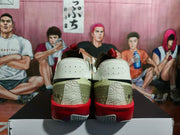 Rear view of the pair showing olive heel panels, raised heel graphics, red midsoles, and textured outsoles.