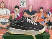 Side profile showing black low-top sneakers with mesh panels, layered detailing, white midsoles, and cream-colored outsole sections.