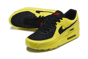 Angled top view of yellow and black Nike Air Max 90 sneakers with black laces.