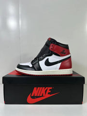 Side profile of the black, white, and red high-top sneaker displayed on a shoebox.
