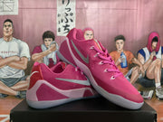 Angled view of pink basketball shoes showing side logos, pale pink heel details, and low-cut shape.